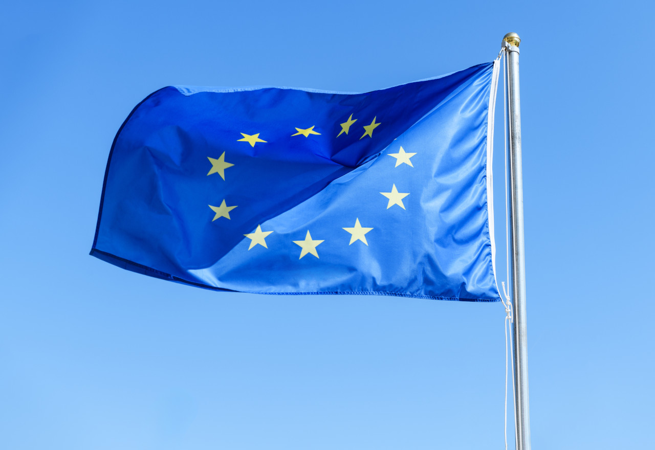 The European Union Flag is gracefully waving in the gentle breeze against a clear bright sky
